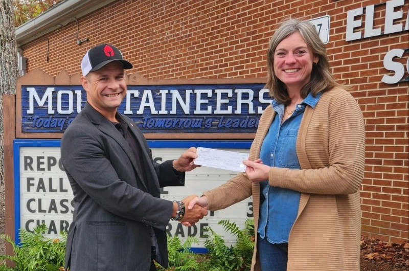 A man and a woman are shaking hands in front of a brick building.