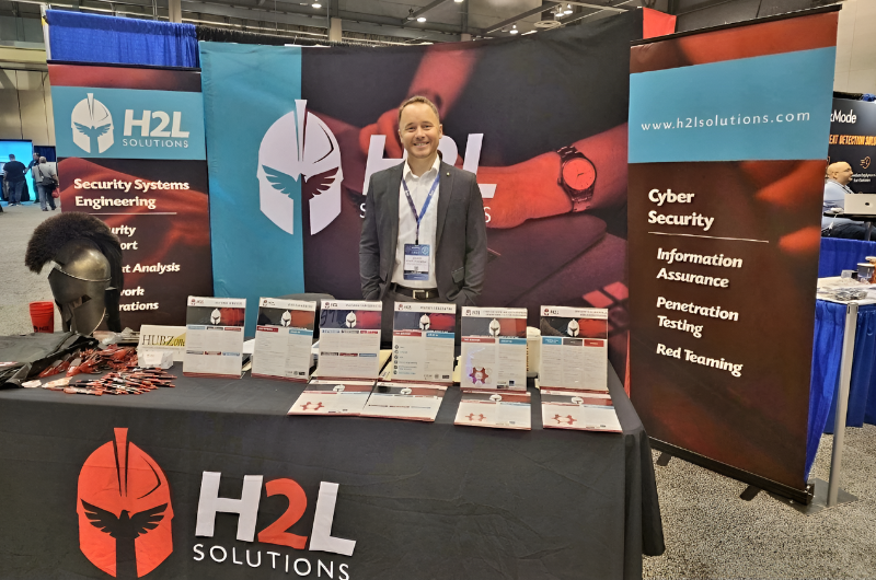 A man is standing in front of a table that says h2l solutions