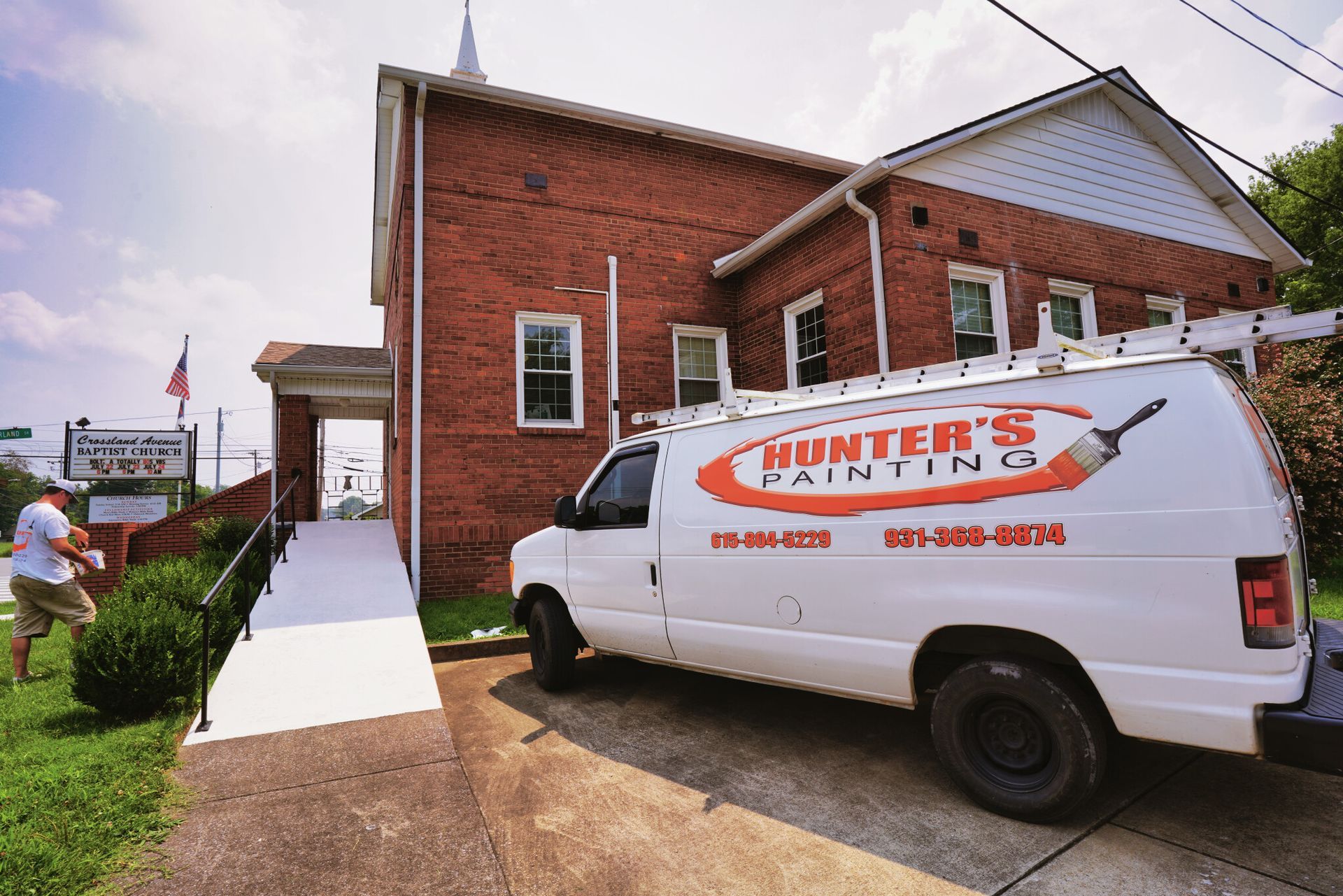 A hunter 's painting van is parked in front of a brick building