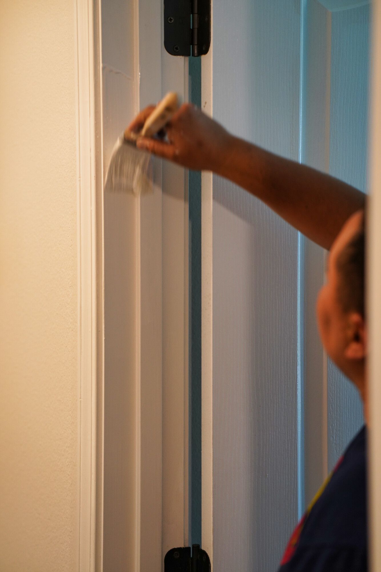 A person is painting a door with a brush.