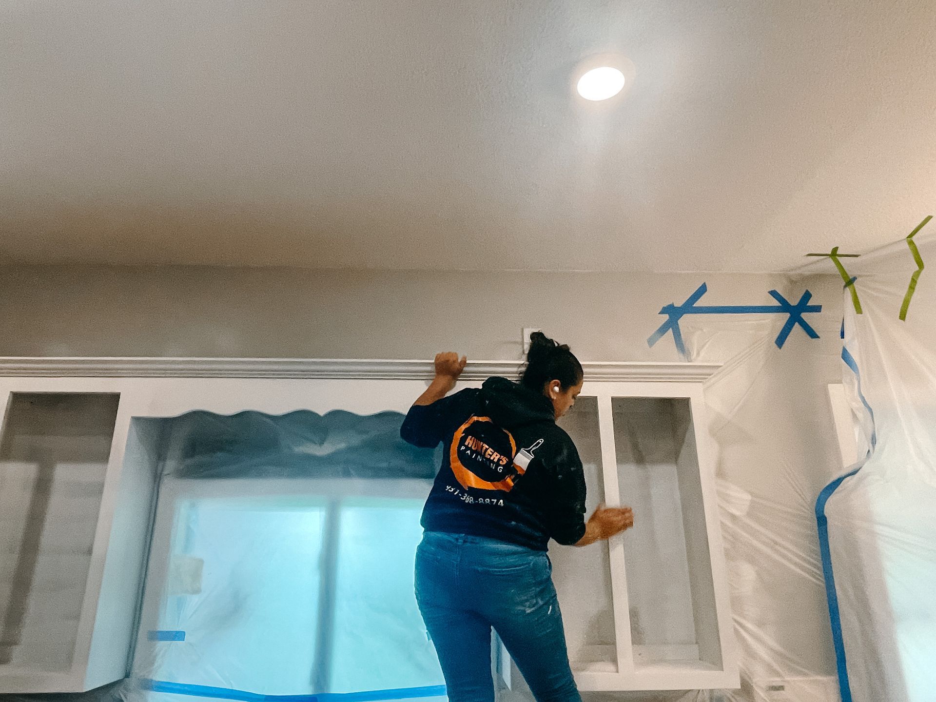 A woman is painting a wall in a room.