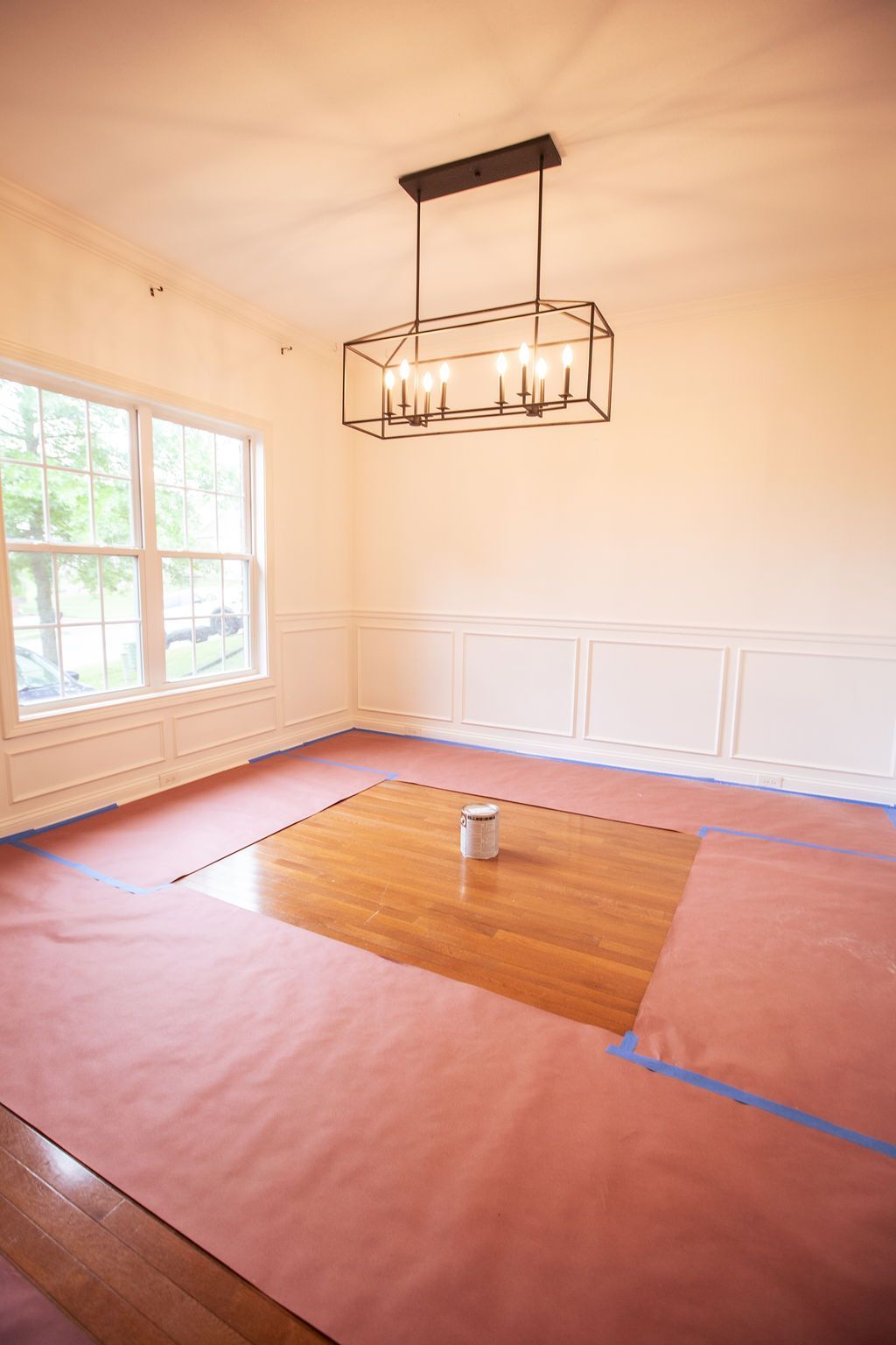 An empty dining room with a chandelier hanging from the ceiling.