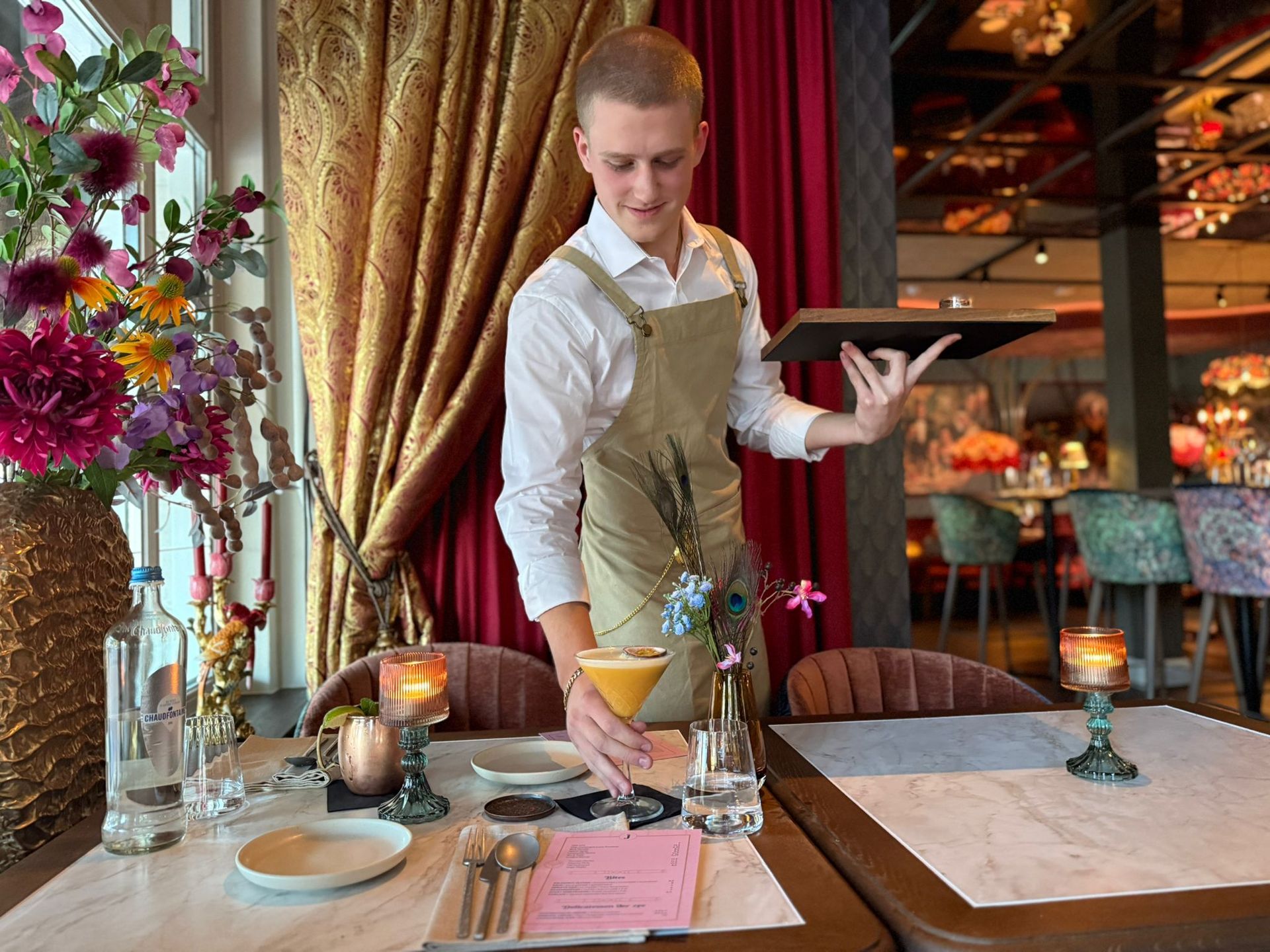 De chef-kok garneert het gerecht met paddenstoelen met een lepel op een houten schaal, omgeven door rook van droogijs.