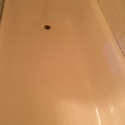 An empty, light-colored rectangular bathtub with a central drain, viewed from above.