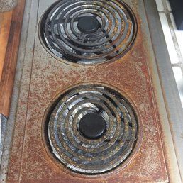 A heavily rusted, two-burner electric stovetop built into a kitchen counter.
