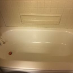 A white bathtub with a tiled wall surround and a built-in shelf.