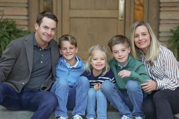 A family is posing for a picture on the porch of their house.