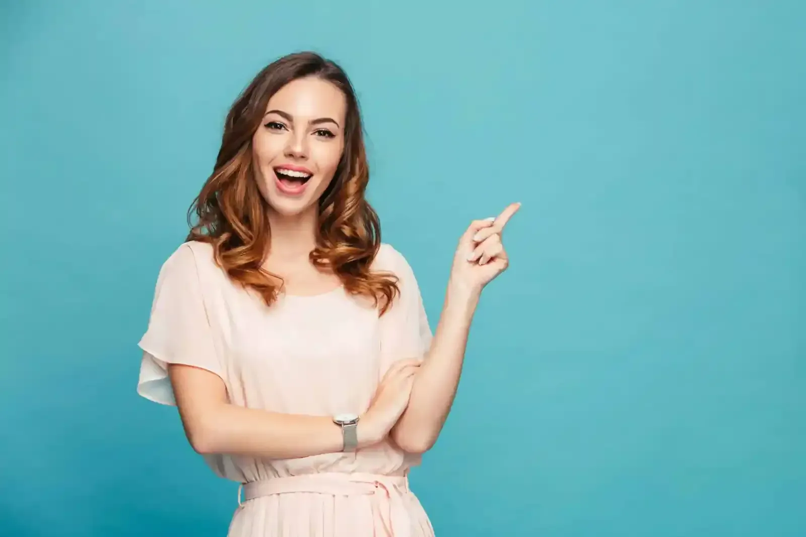 Portrait of a smiling woman pointing finger at something over blue background