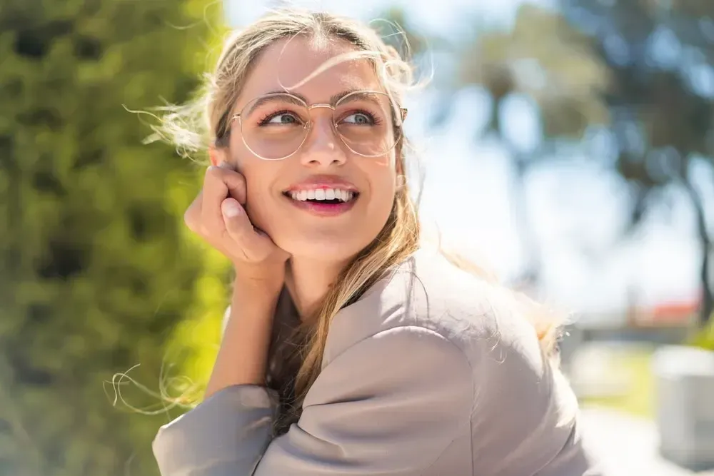 A woman wearing glasses is smiling and looking up.