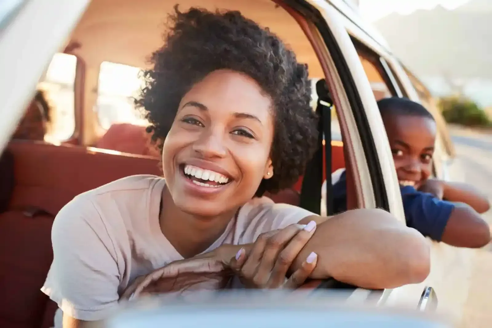 A woman and a child are sitting in a car and smiling.