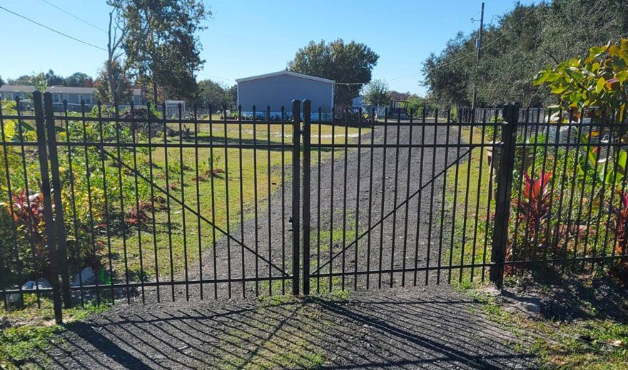 A metal gate is open to a dirt road.