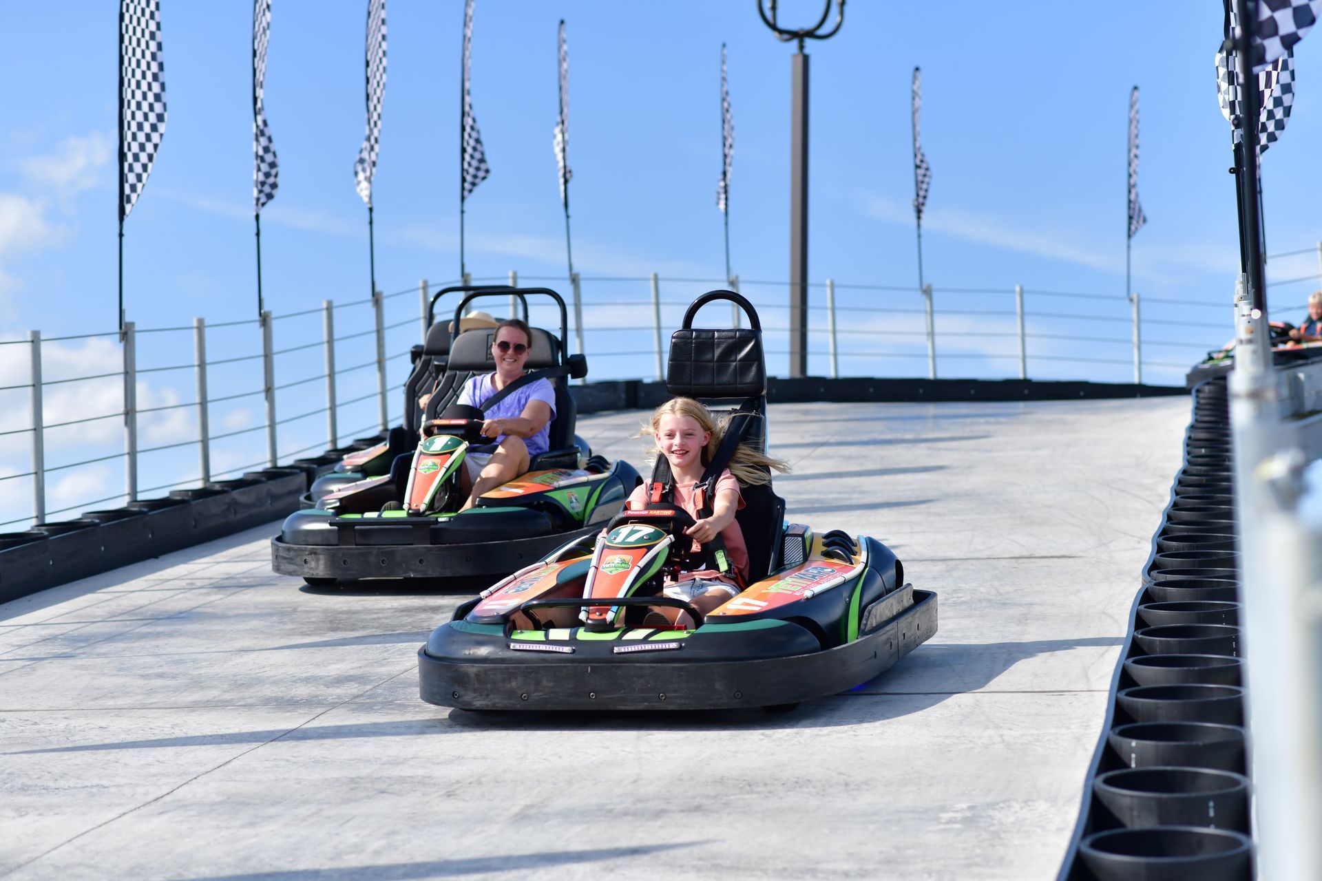 A man and a woman are riding go karts on a track.