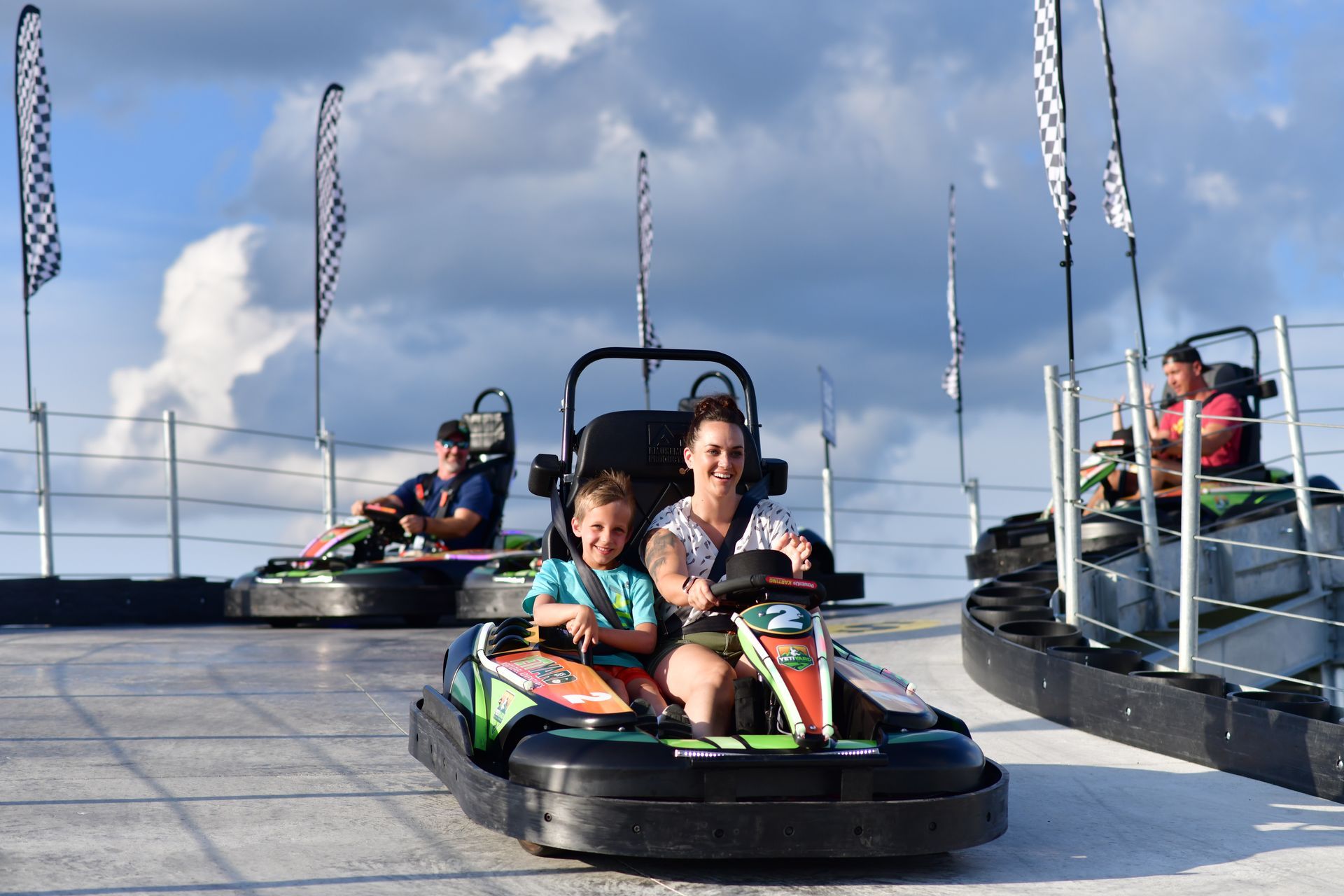 A woman and two children are riding go karts on a track.