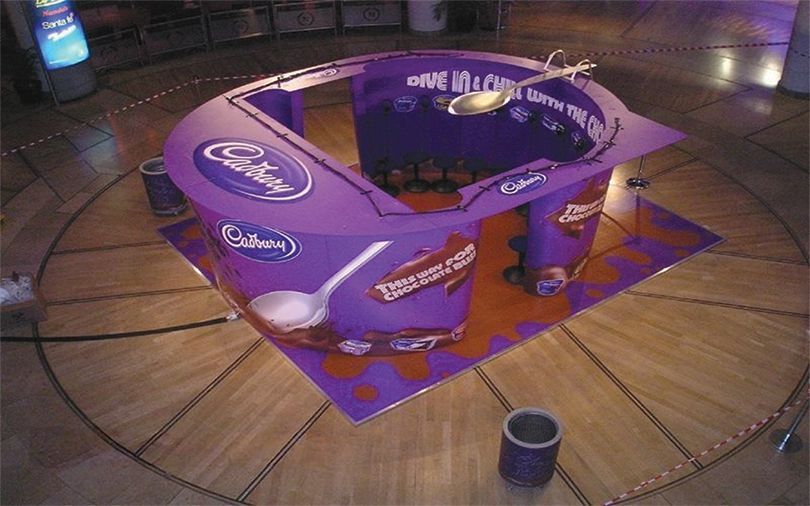 A purple cadbury display on a wooden floor