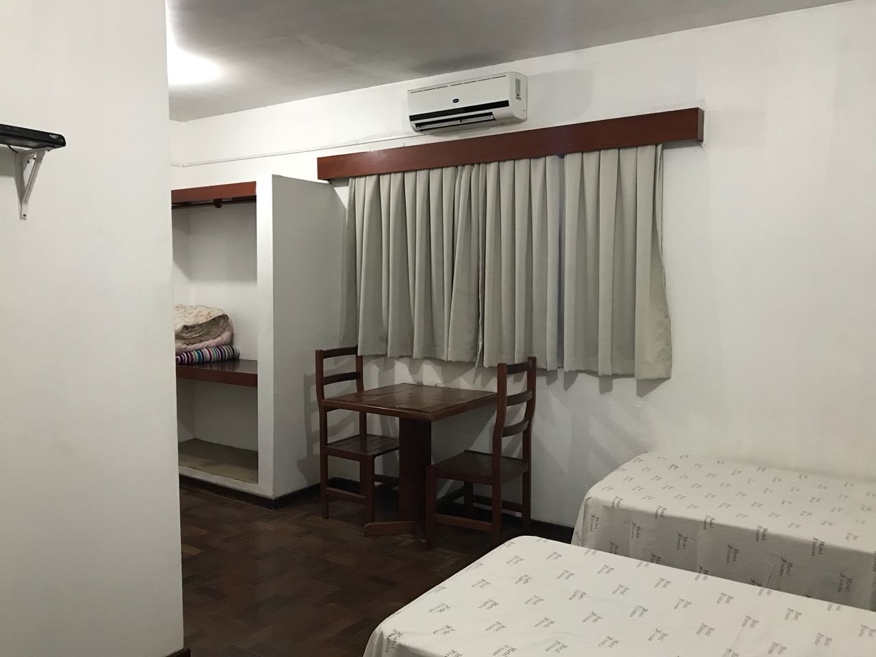 Um quarto de hotel com duas camas, uma mesa e cadeiras.