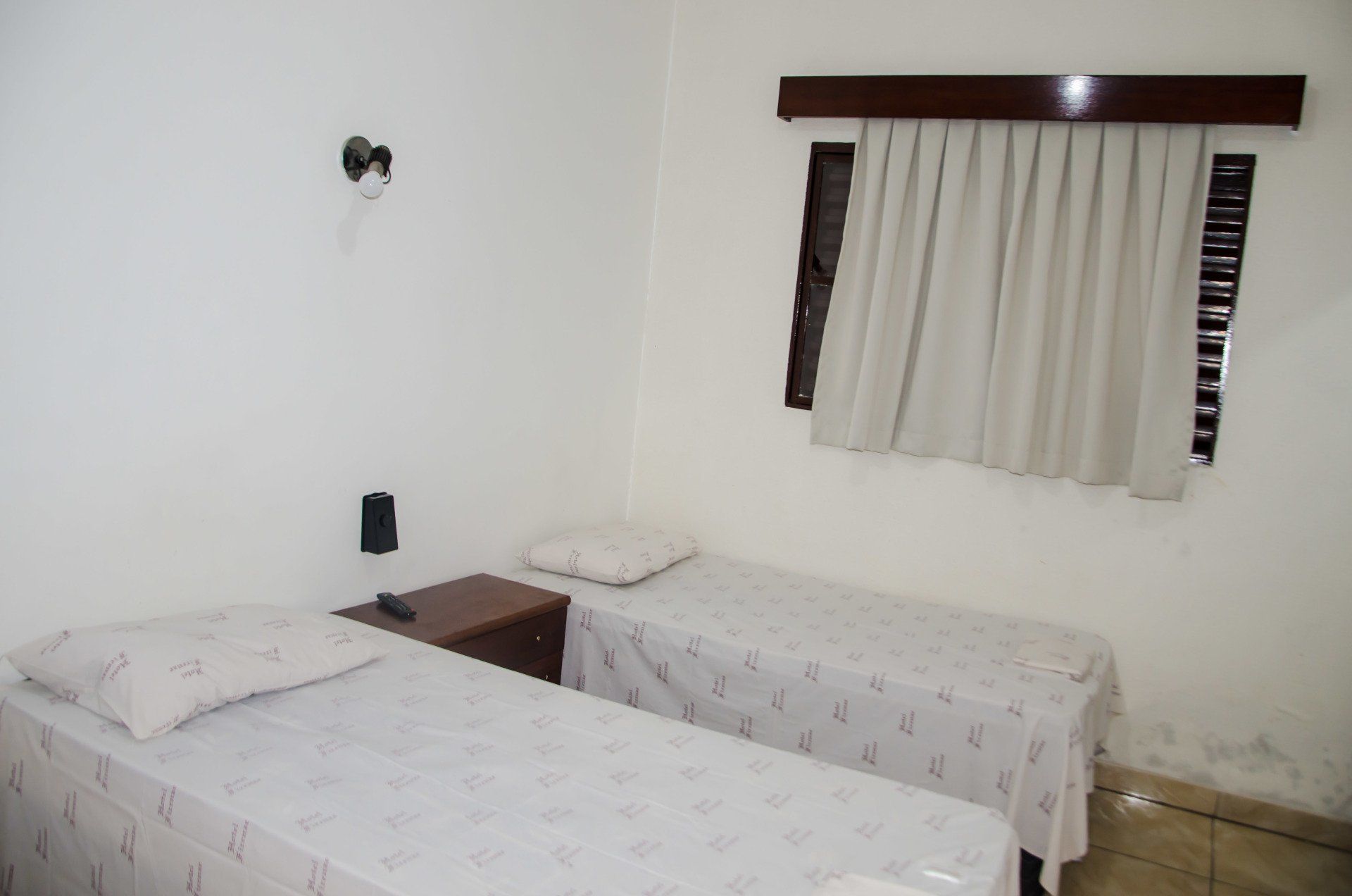 Um quarto com duas camas de solteiro e uma janela