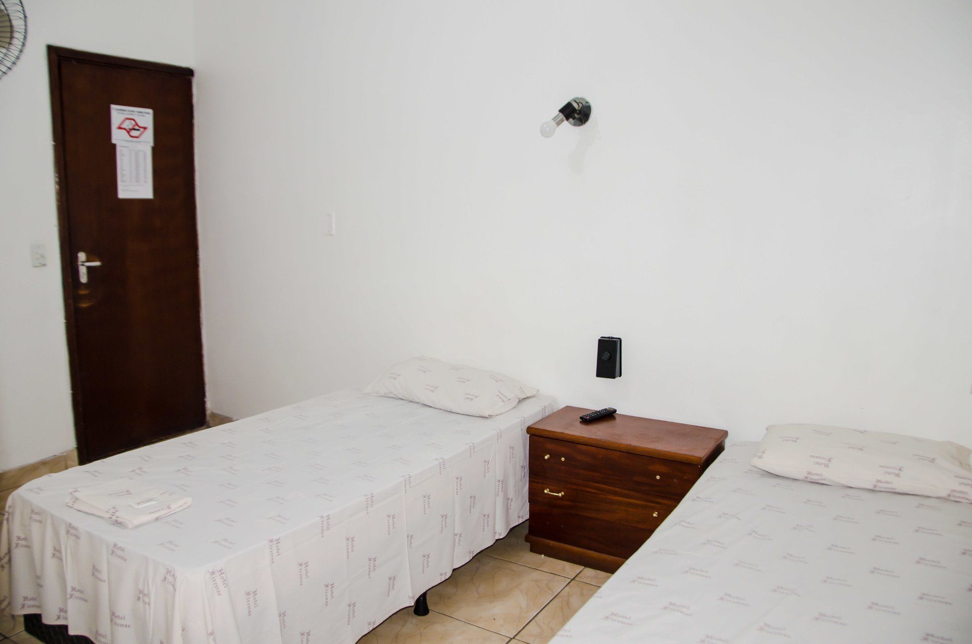 Um quarto com duas camas e uma mesa de cabeceira.