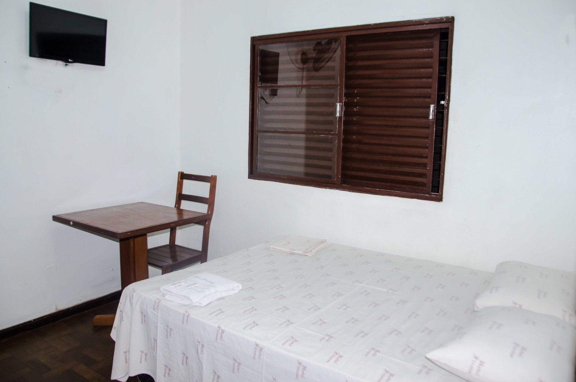 Um quarto com uma cama uma mesa e uma televisão