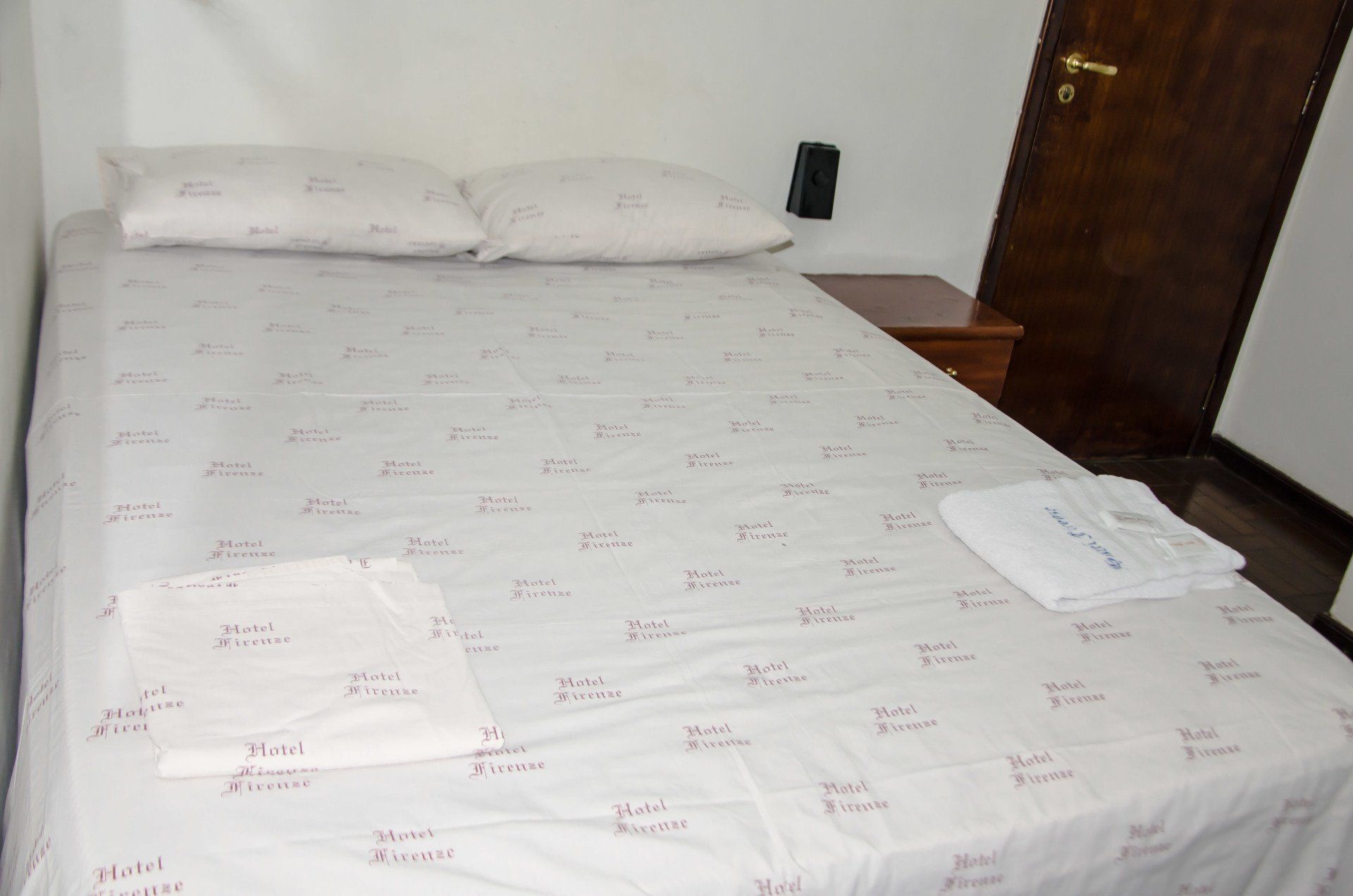 Uma cama com lençóis e travesseiros brancos em um quarto de hotel