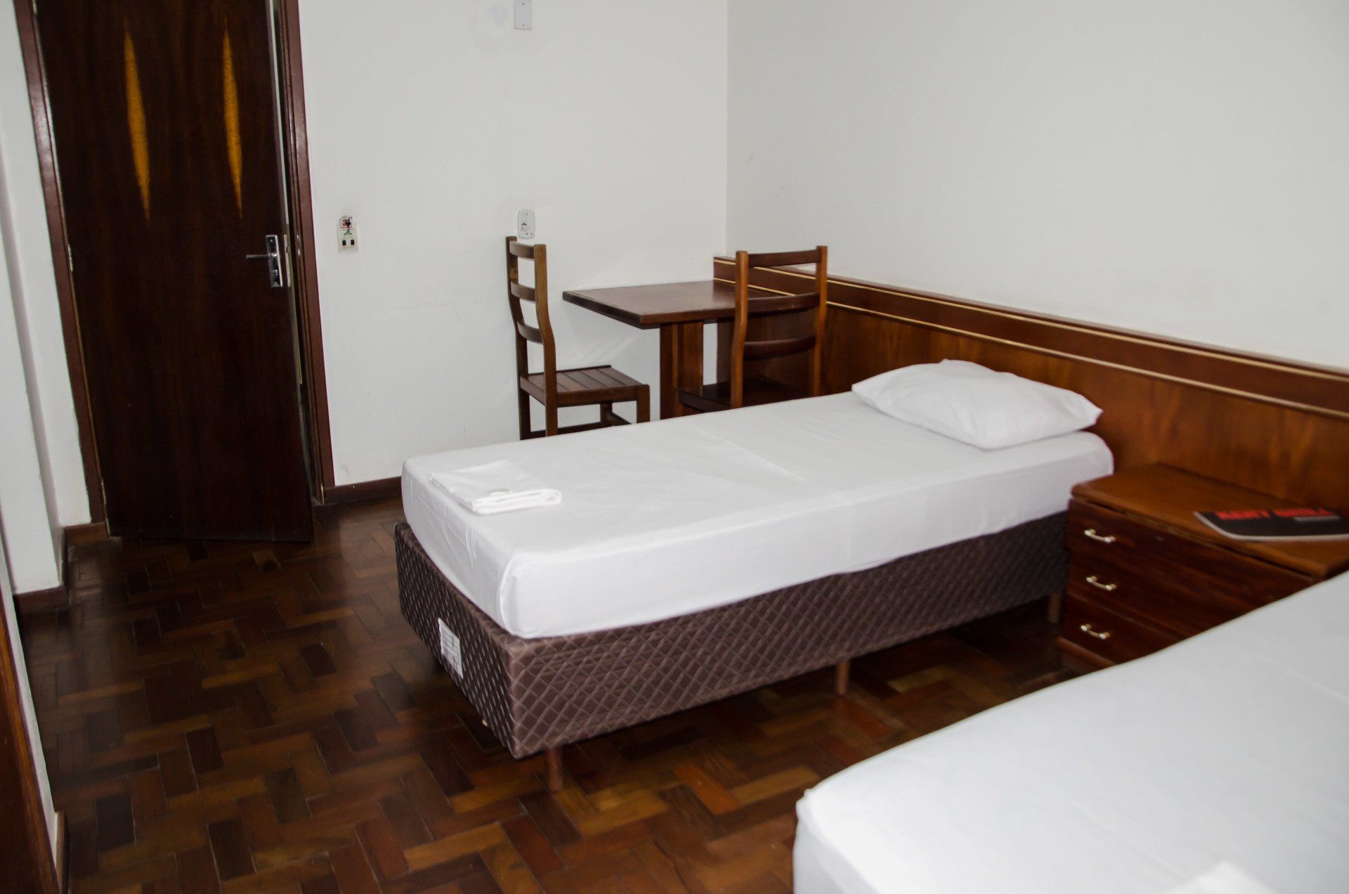 Um quarto de hotel com duas camas, uma mesa e cadeiras