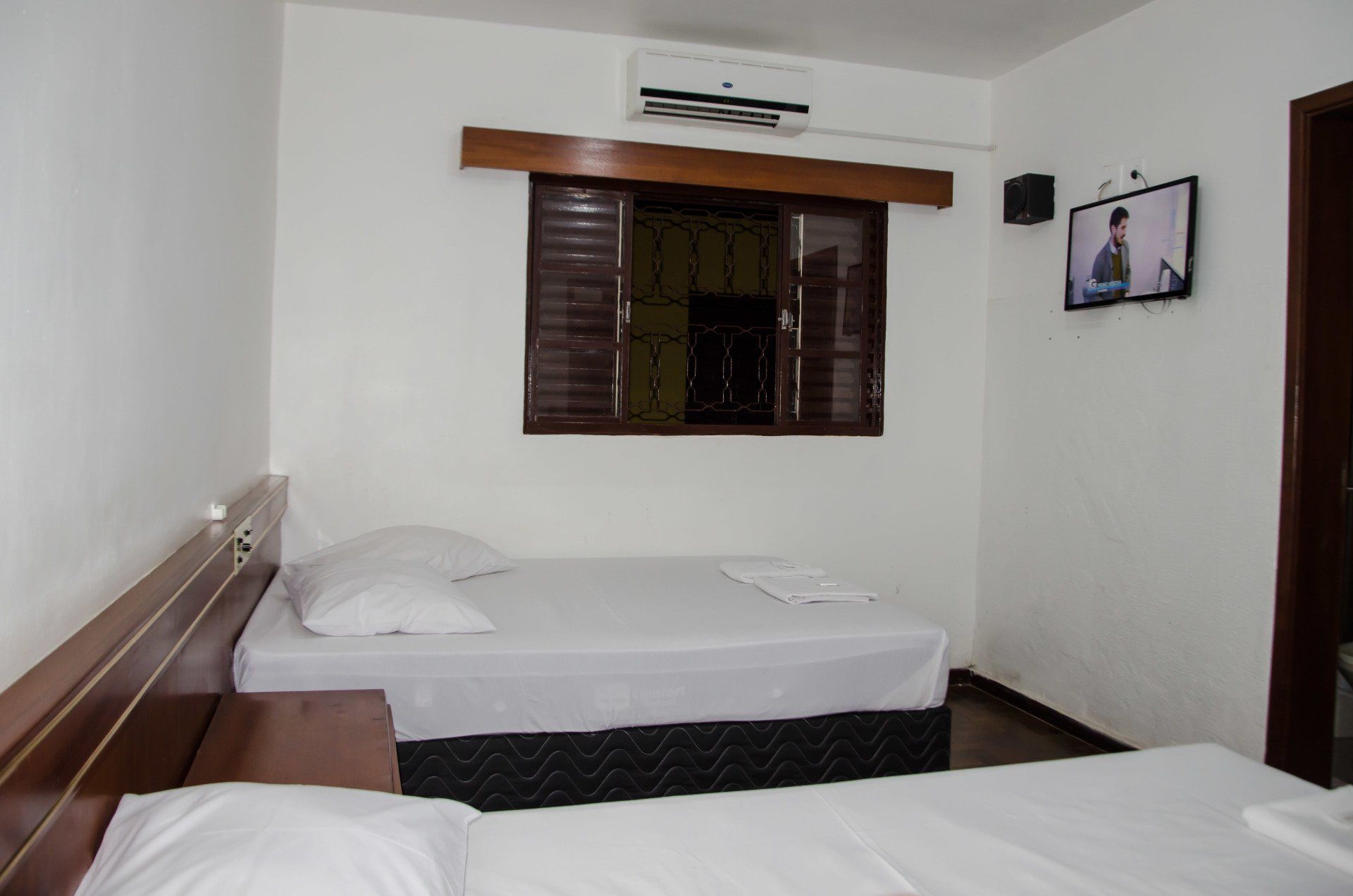 Um quarto de hotel com duas camas e uma televisão na parede