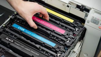 A person is taking a toner cartridge out of a printer.