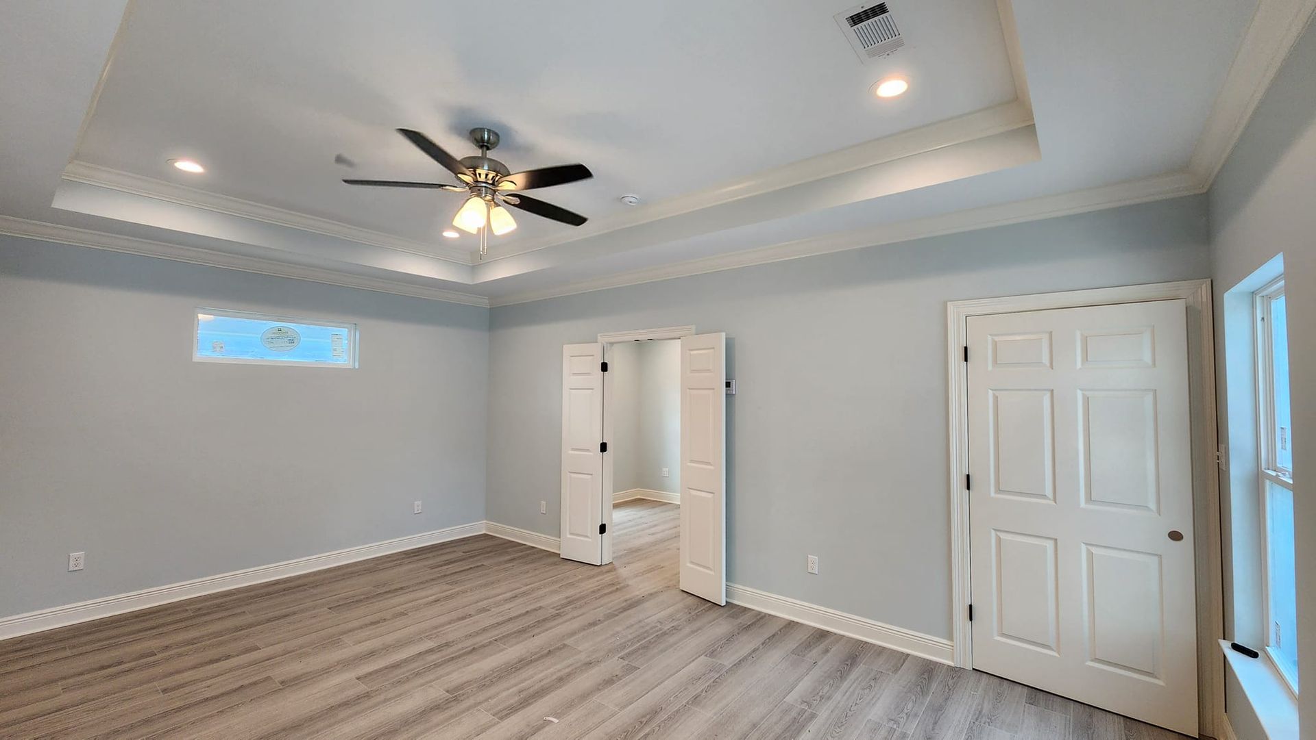 Home Addition - Bedroom with light blue walls, tray ceiling, closet, and white doors.