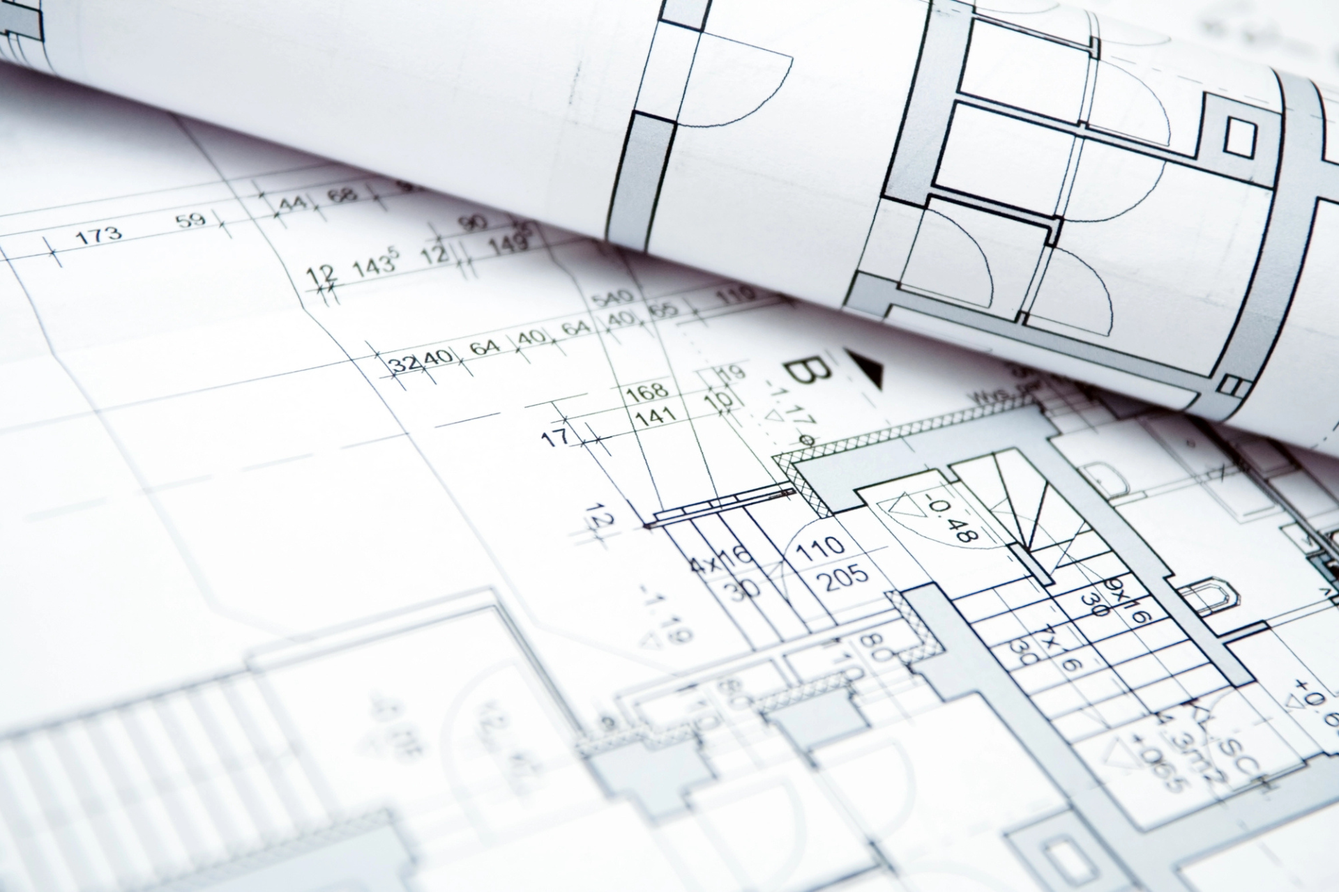 Close-up of rolled architectural blueprints on a desk, displaying detailed floor plans