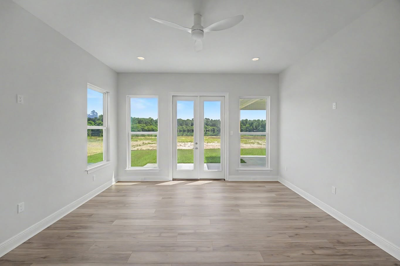 Bright room with French doors, tall windows, recessed lighting and wood-look floors