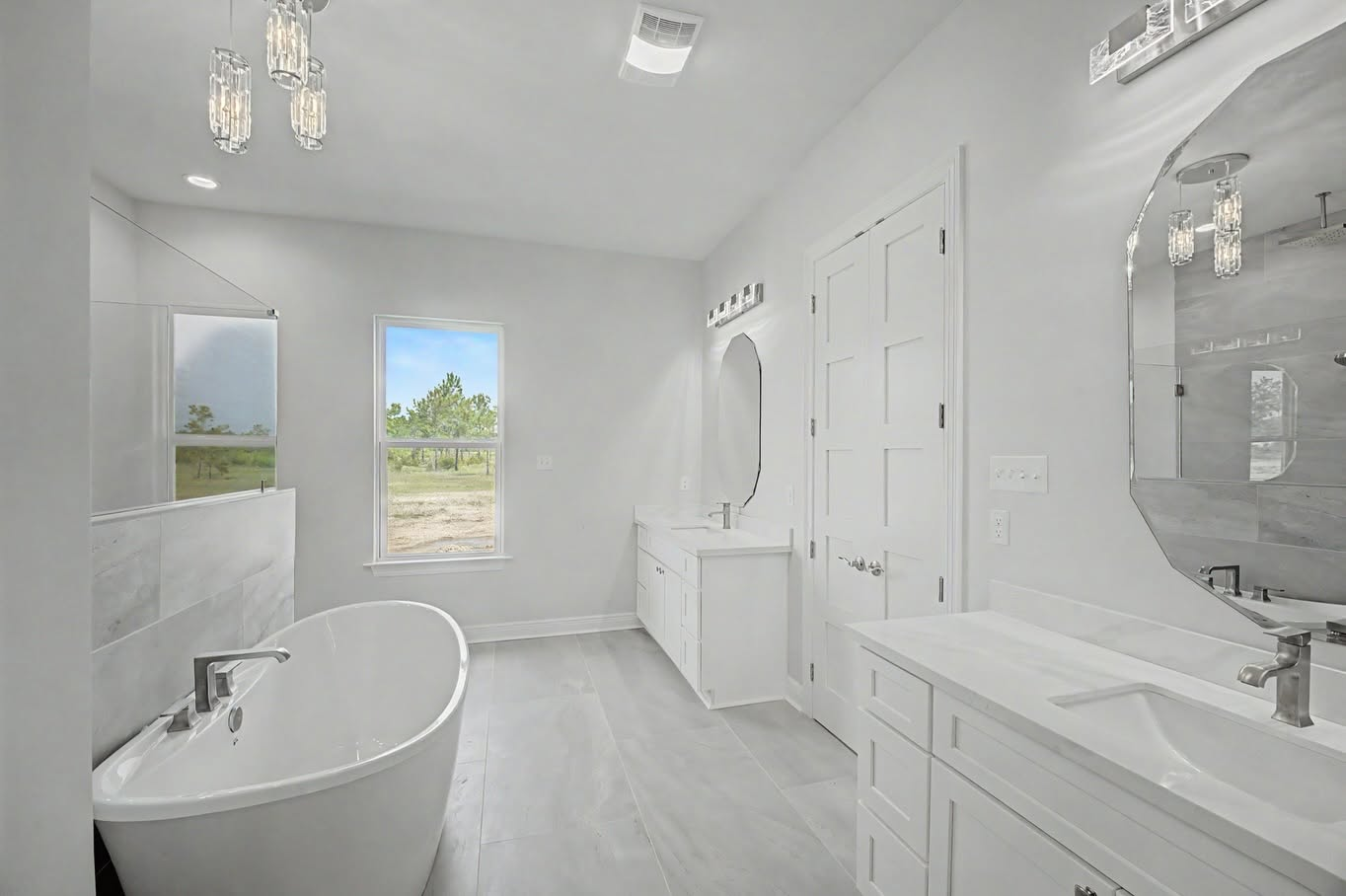 Bright primary bathroom with a freestanding tub, dual vanities and modern mirrors
