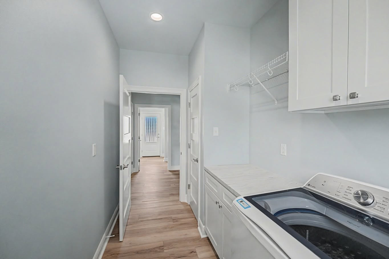 Custom laundry room with white cabinets, countertop workspace and hanging storage