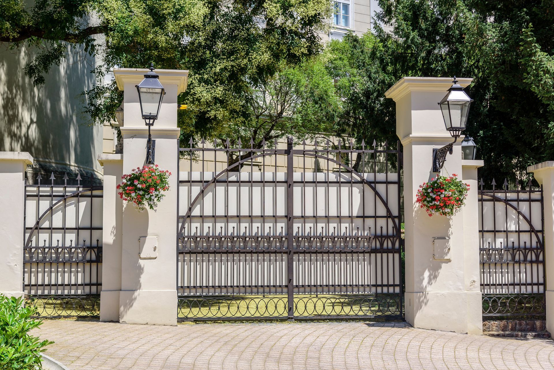 Wrought iron gates with stone pillars and hanging flower baskets.