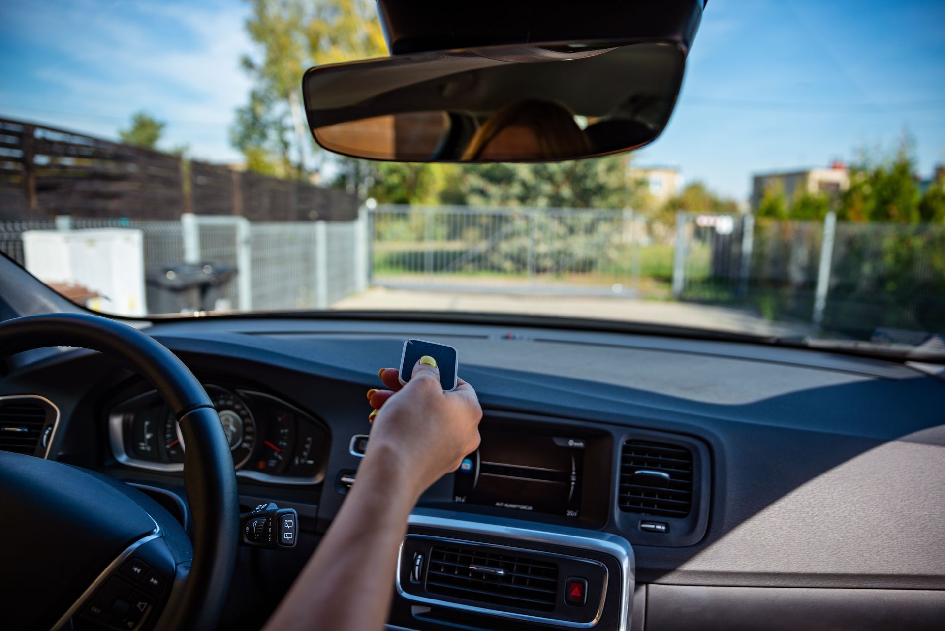 Person in car using remote to open a gate.