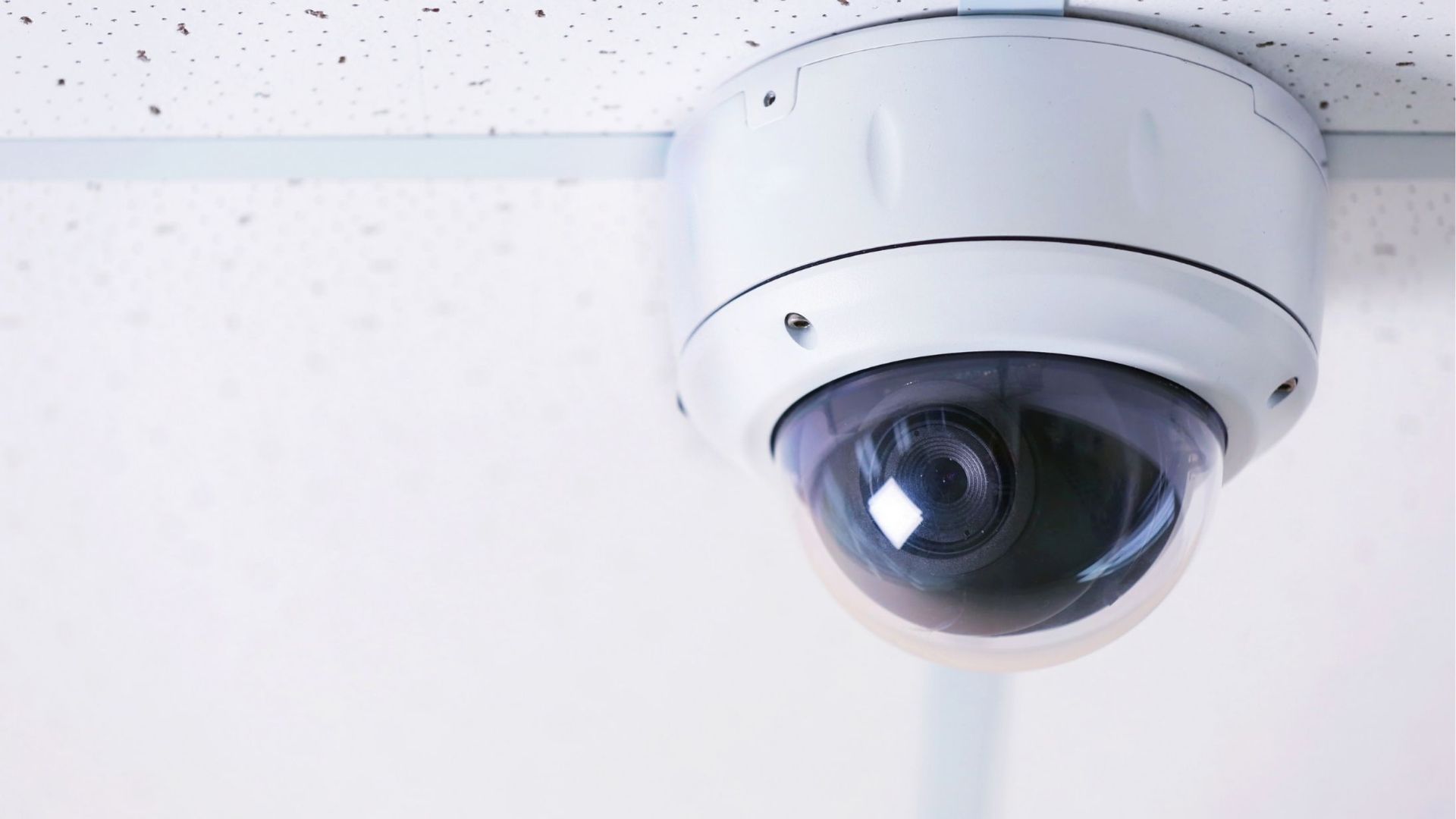White security camera mounted on a white ceiling.