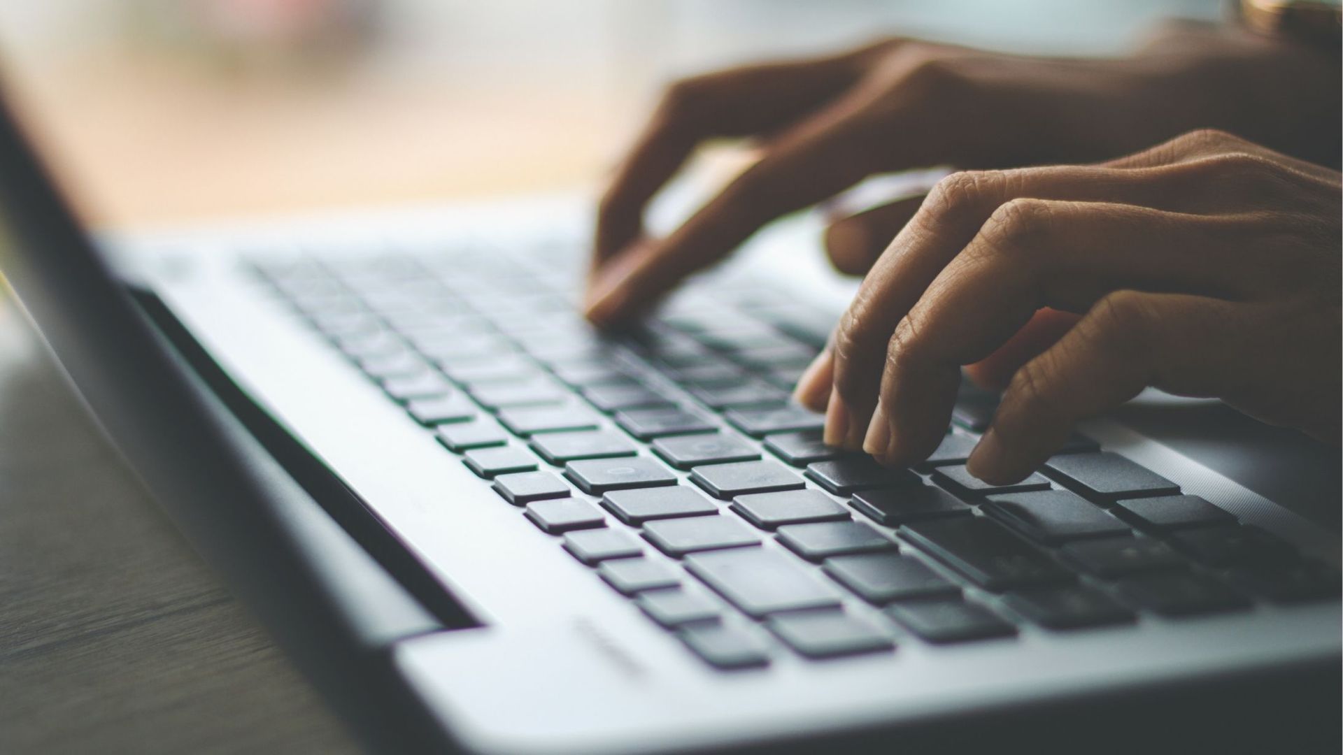 Hands typing on a laptop keyboard; close-up view.