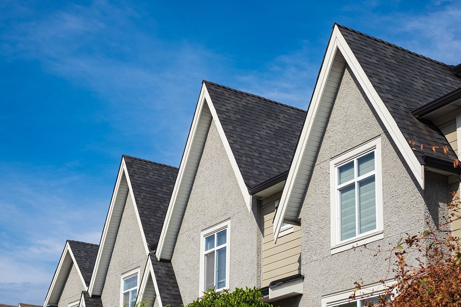 Row of gray townhouses with steep gabled roofs under a blue sky Row of gray townhouses with steep gabled roofs under a blue sky