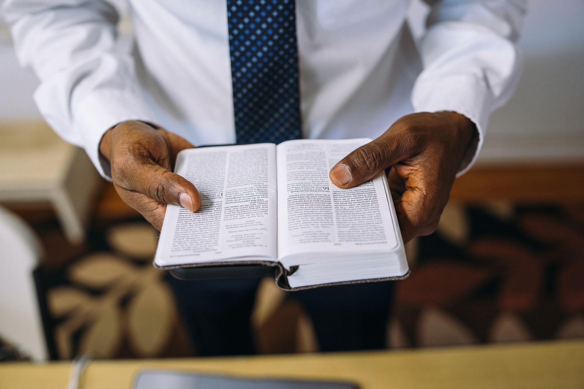 A man in a white shirt and tie is holding a bible in his hands.
