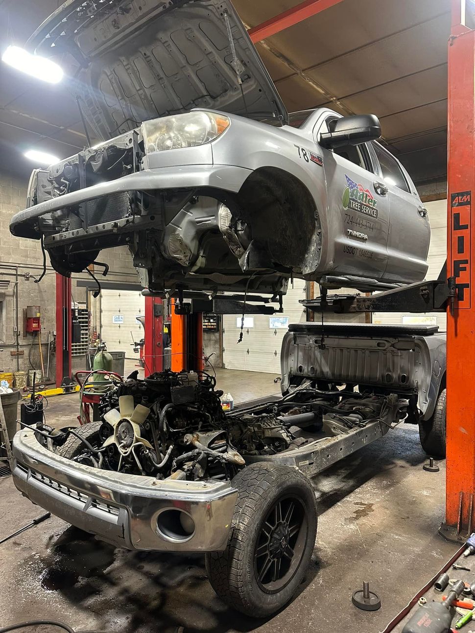 A truck is sitting on top of a lift in a garage.