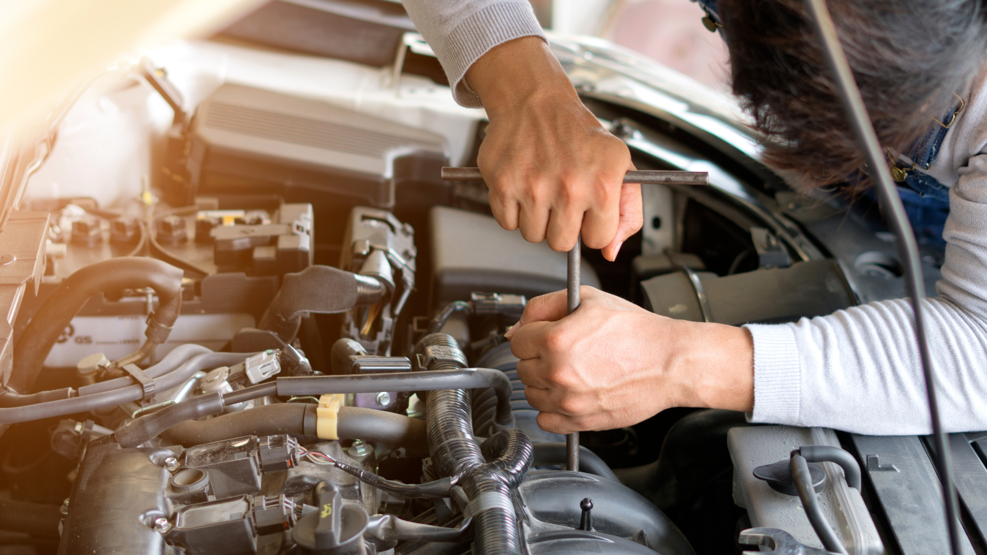 A man is working on the engine of a car with a wrench.