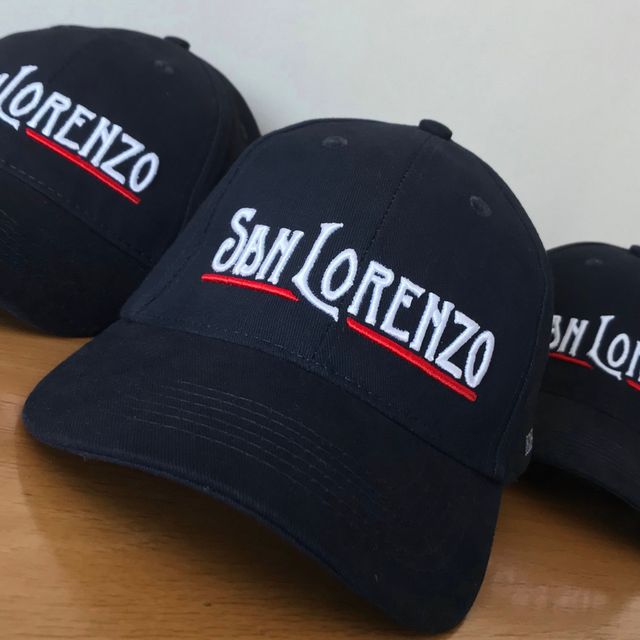 Tres gorras de béisbol azul marino bordadas con "San Lorenzo" en blanco y rojo.