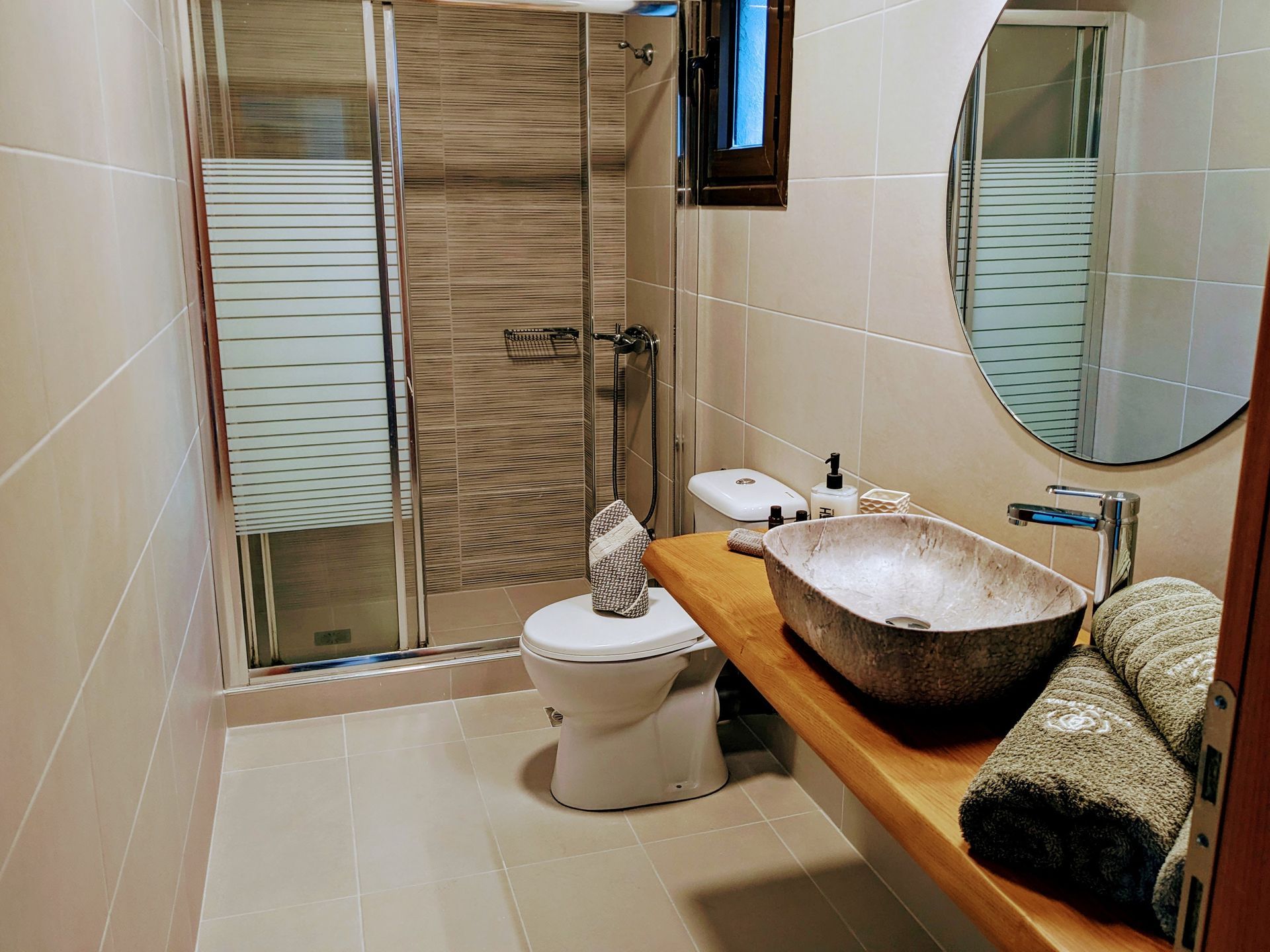 A bathroom with a toilet , sink , mirror and shower.