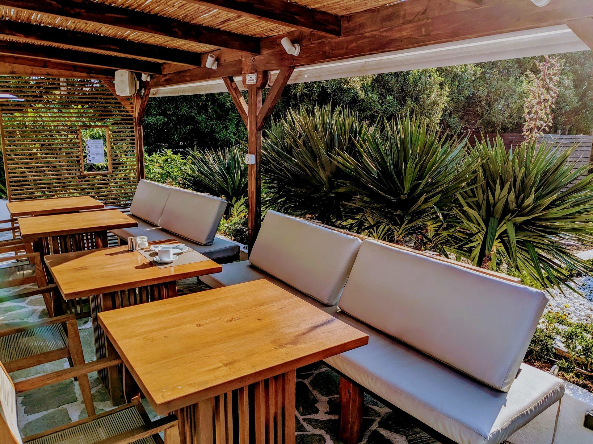 A patio area with tables and benches under a canopy
