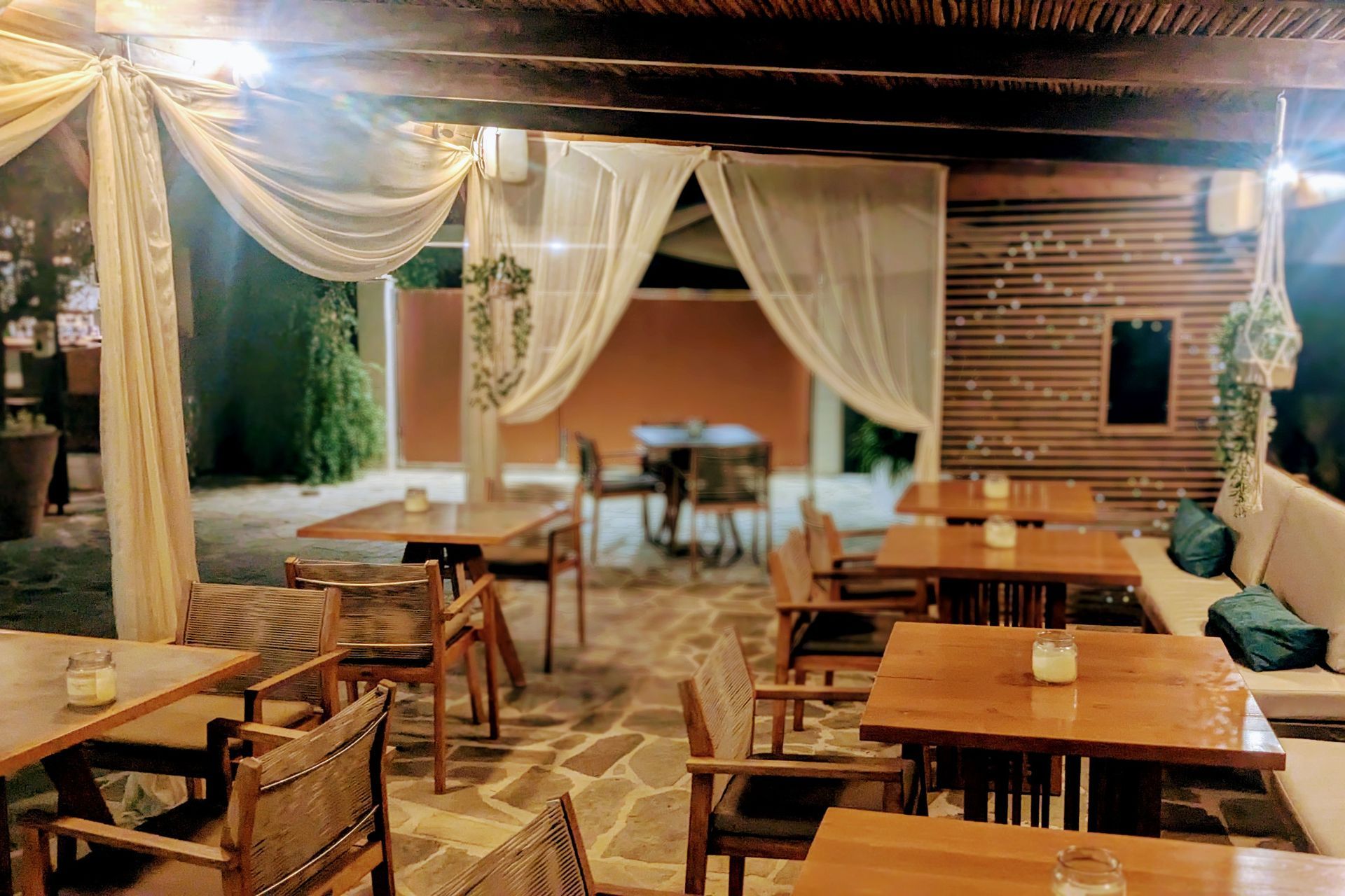 A restaurant with tables and chairs under a canopy.