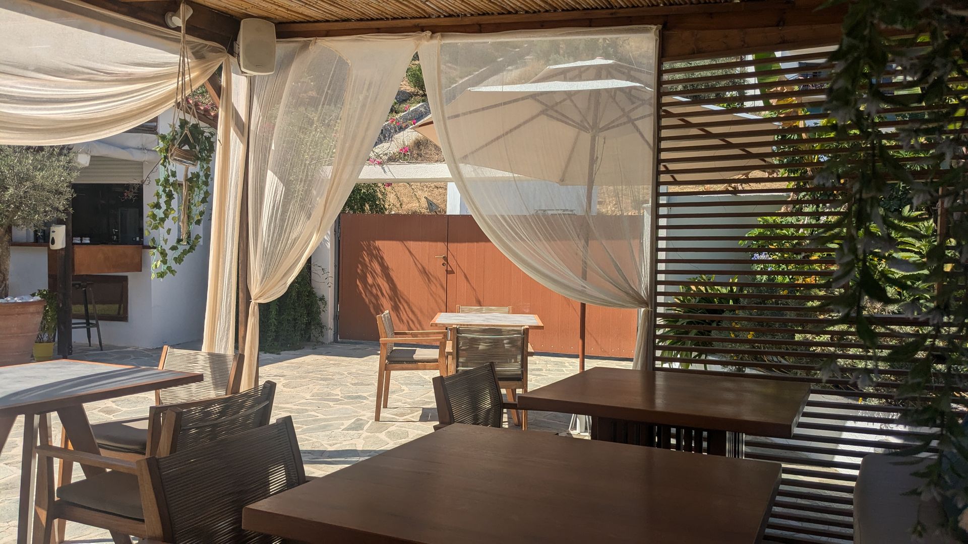 A restaurant with tables and chairs under a canopy with umbrellas.