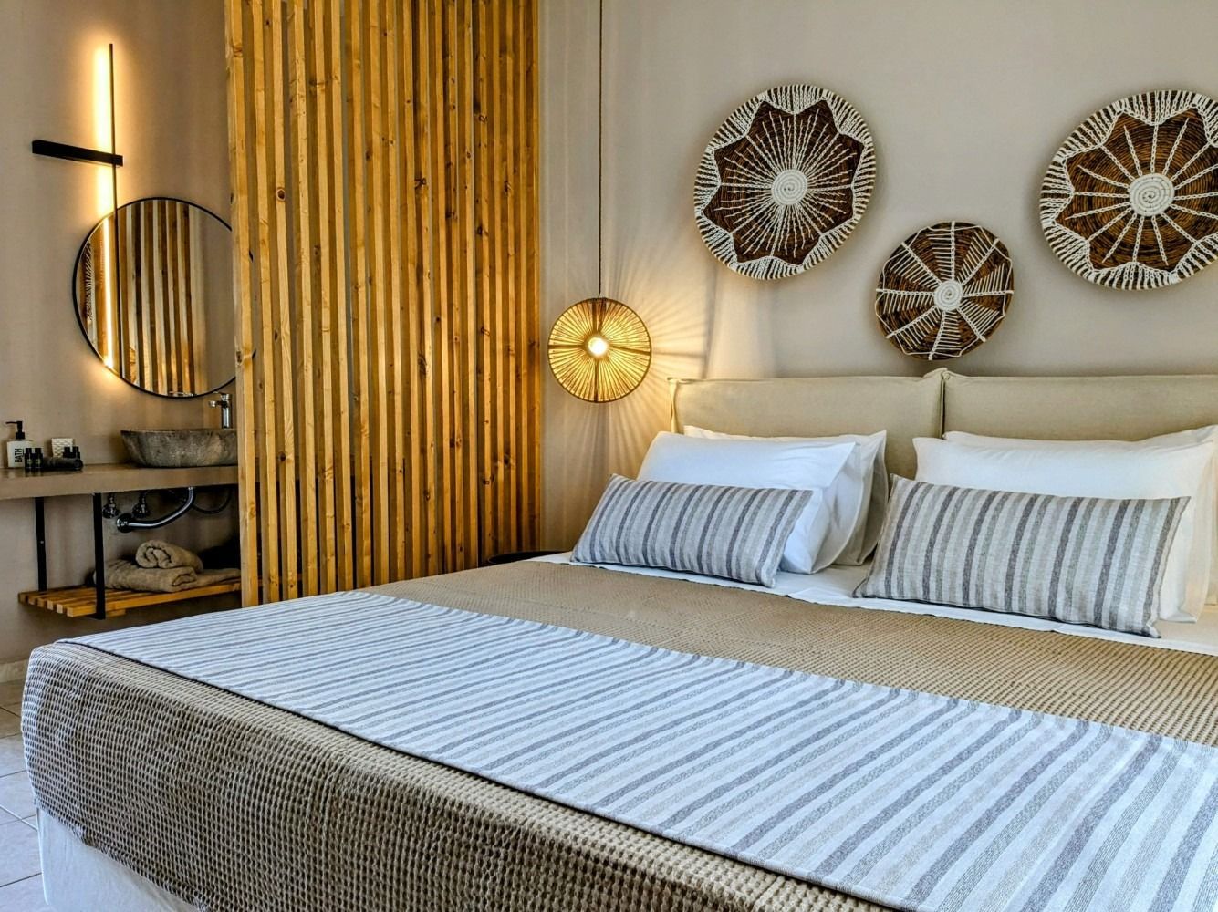 A bedroom with a large bed and a wooden divider between the bedroom and bathroom.