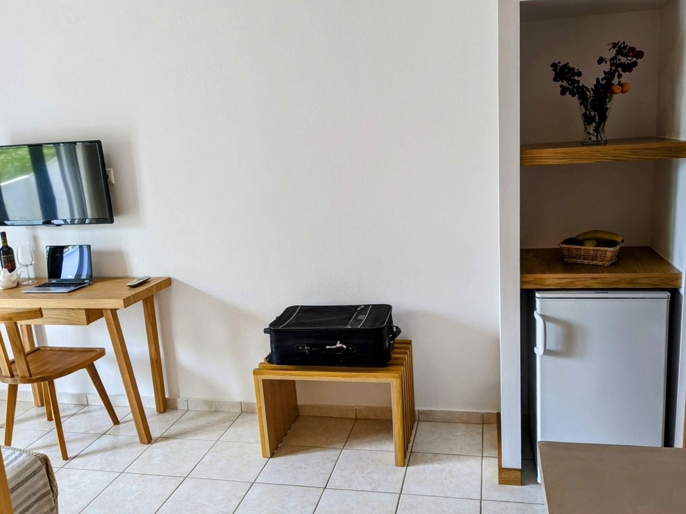 A suitcase is sitting on a small wooden table in a hotel room.