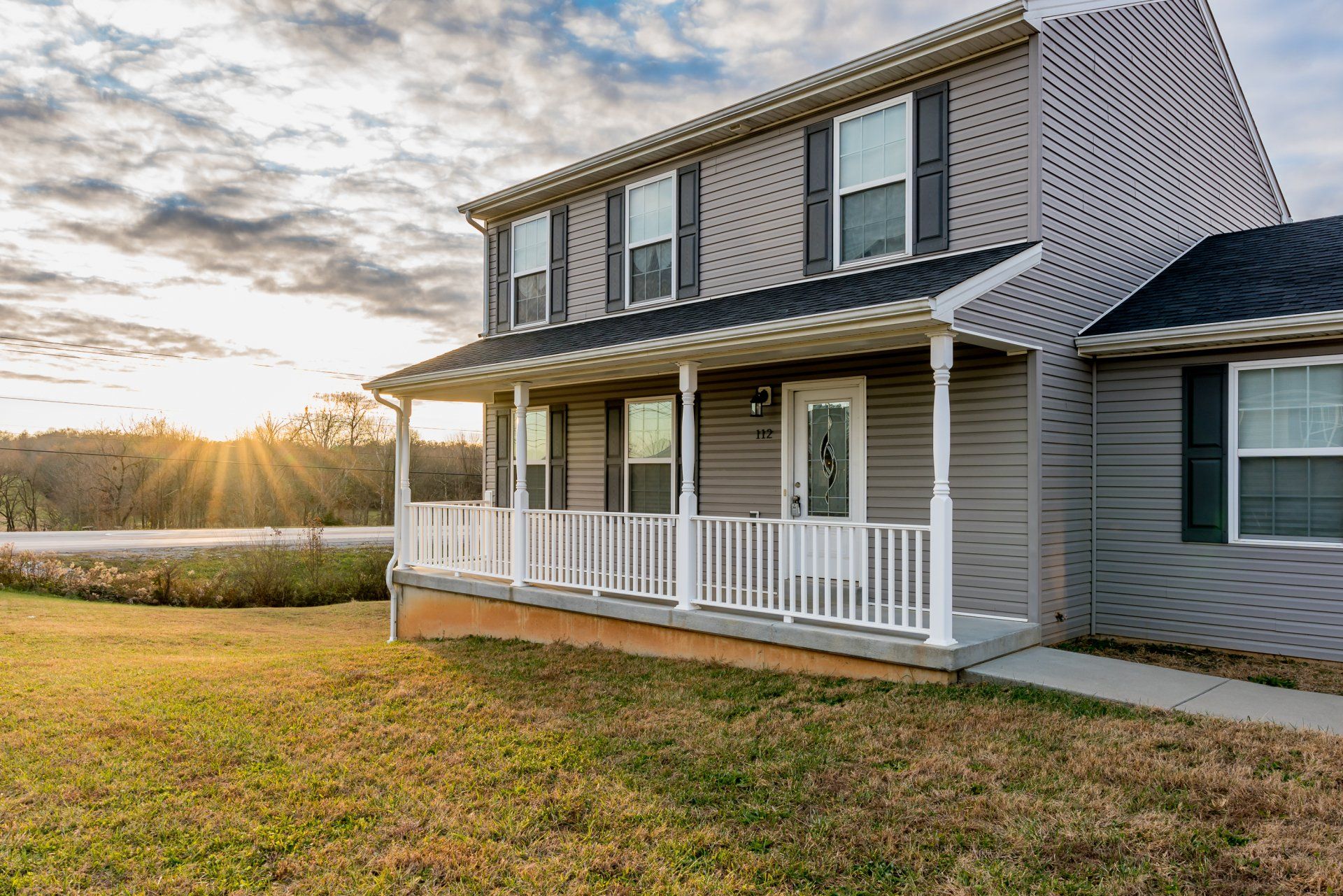 a large house with a large porch and a sunset in the background .