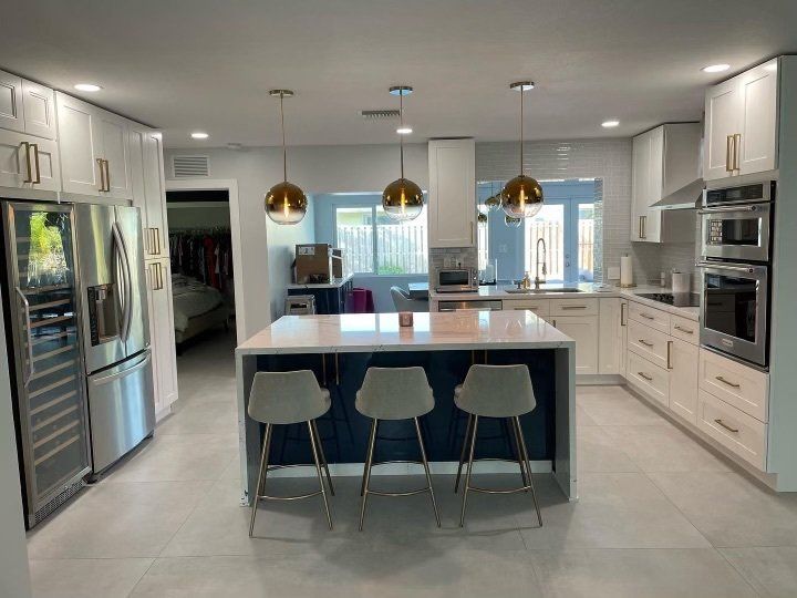a kitchen with white cabinets , stainless steel appliances and a large island .