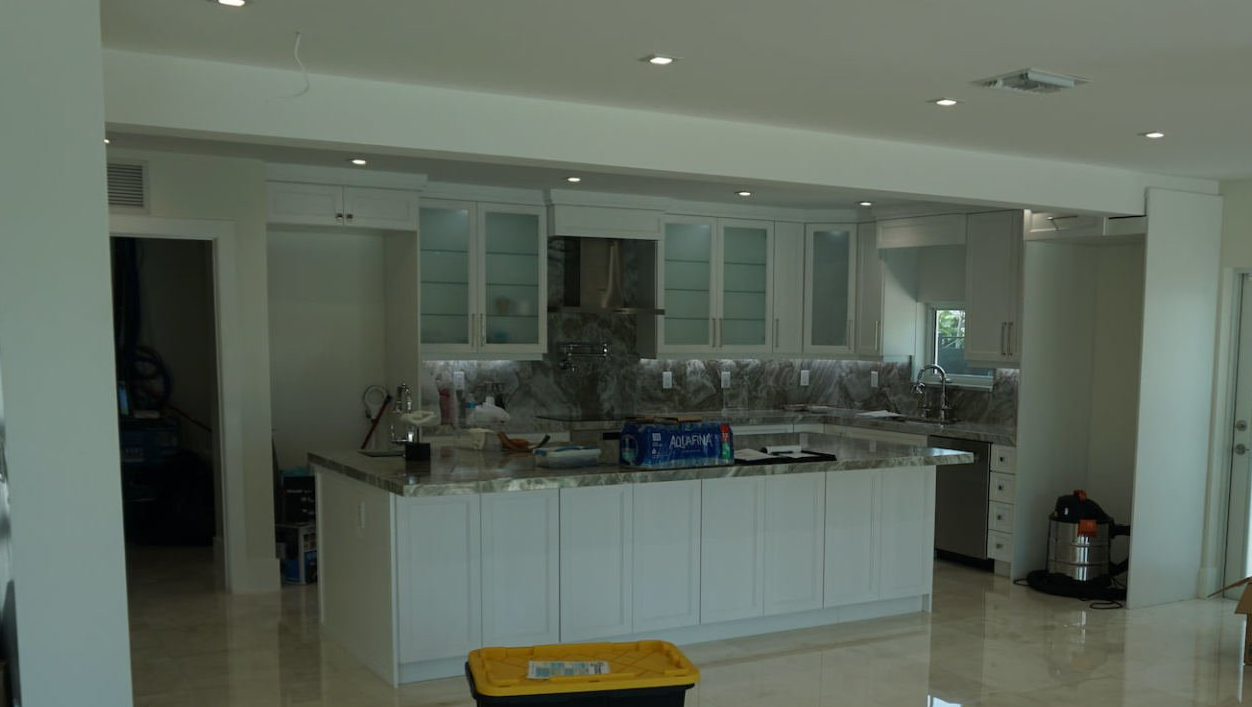 a kitchen with white cabinets and a large island in the middle of the room .