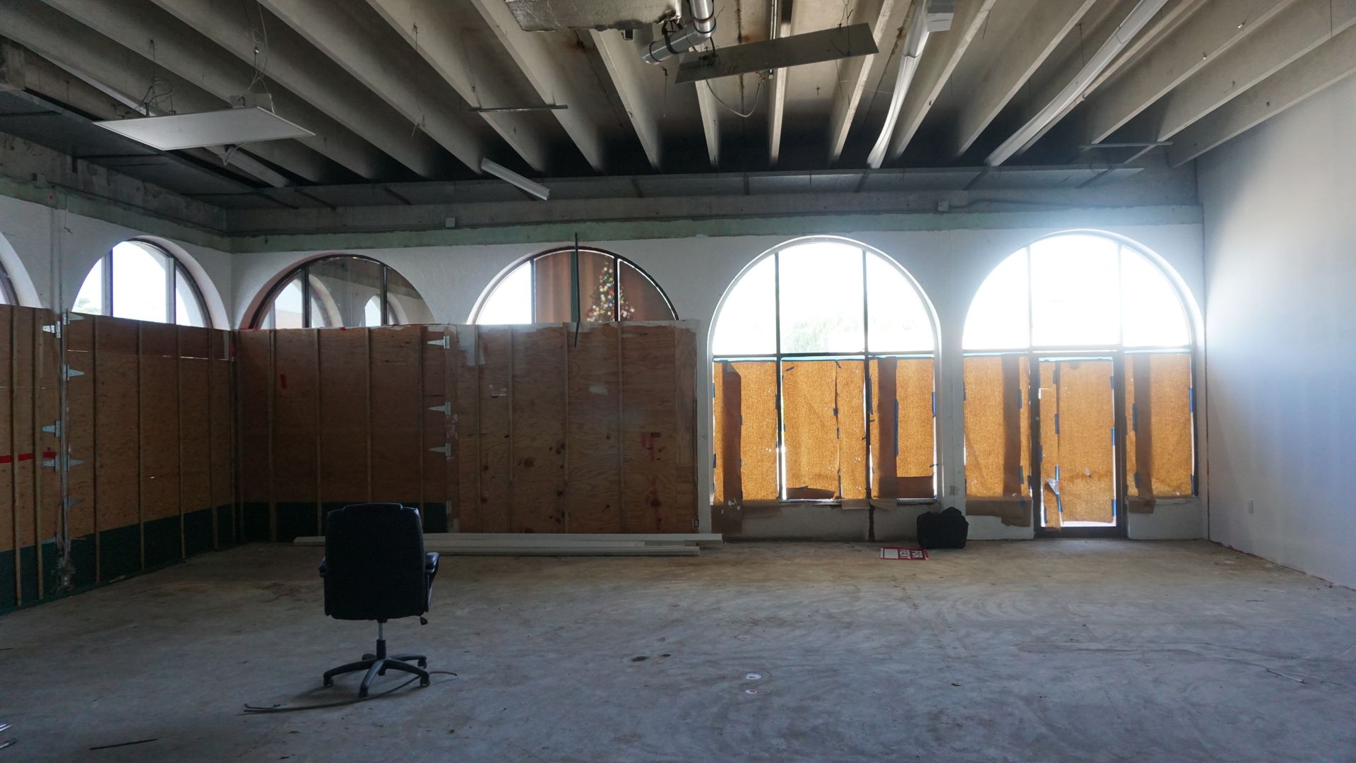 An empty room with arched windows and a chair